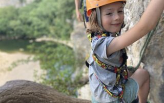 Jeune enfant assis sur l’arbre suspendu en pleine falaise © Kayacorde 