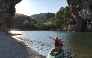 Children's games in a canoe under the Pont d'Arc at sunset